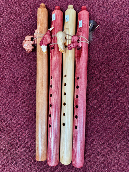 Four wooden flutes of different colors on a purple background